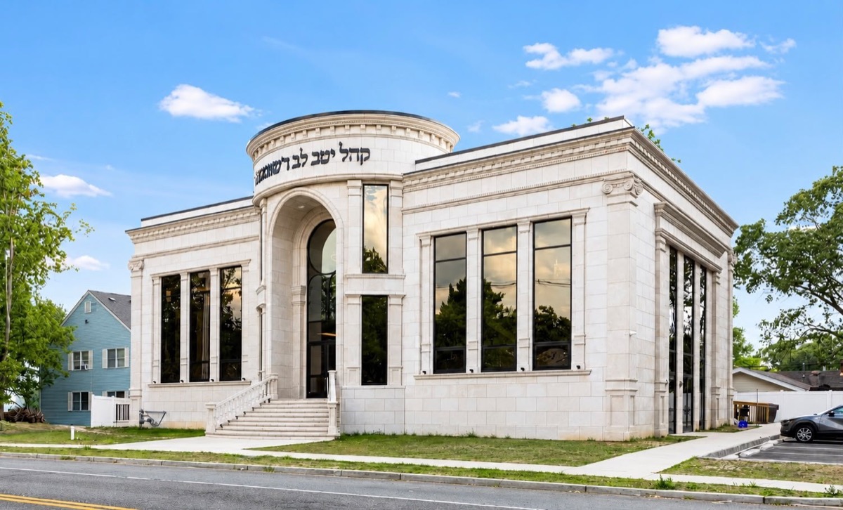 Stone shul with an arched entry, a round drum and tall black windows
